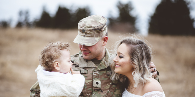 Young family portrait - a soldier father holding his son and a beautiful young wife