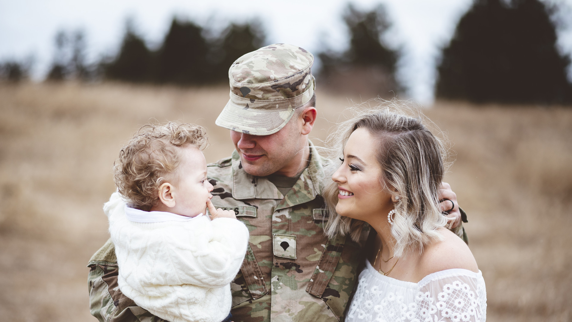 Young family portrait - a soldier father holding his son and a beautiful young wife