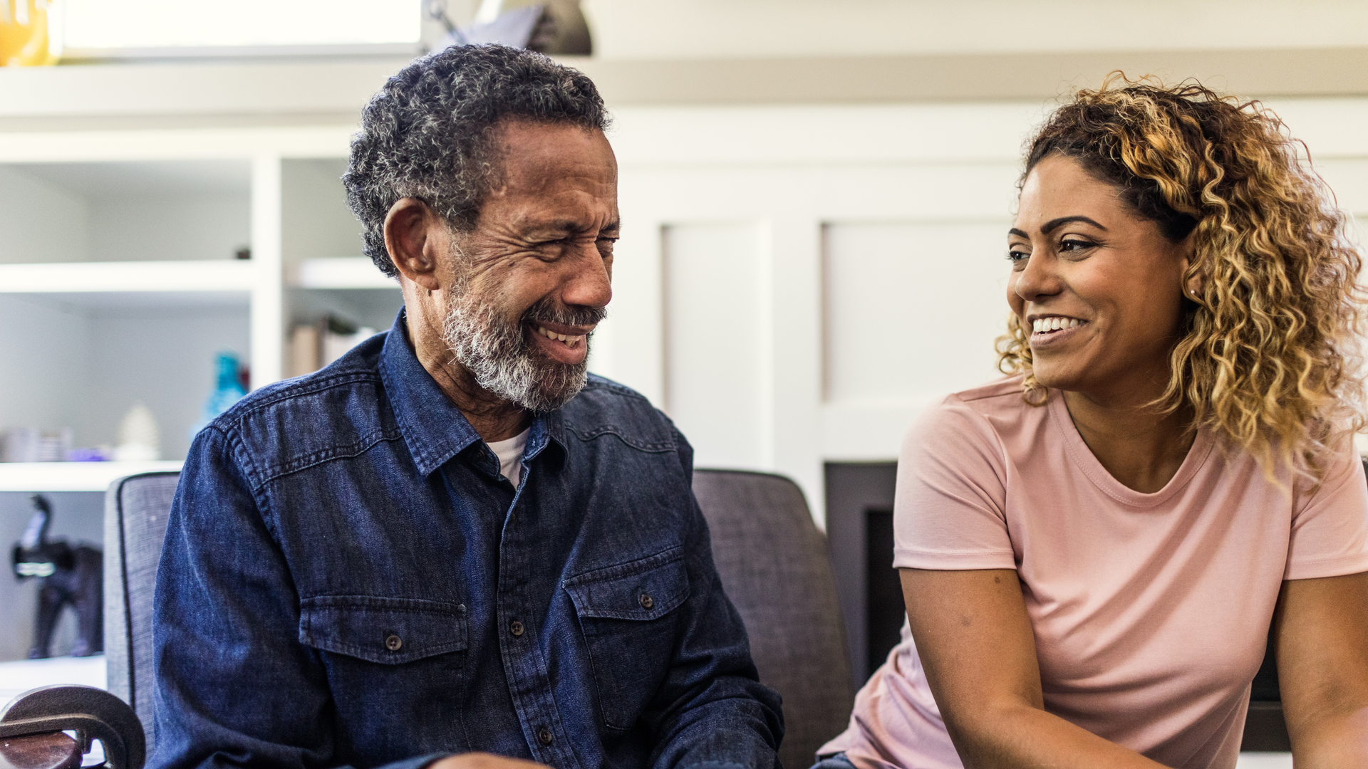 Senior man and adult daughter talking on couch