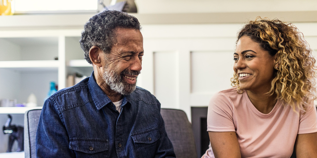 Senior man and adult daughter talking on couch