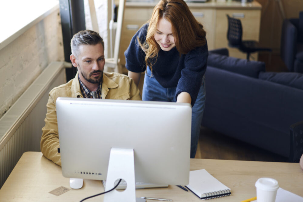 Decorative image of Man and woman sitting at desk in front of computer