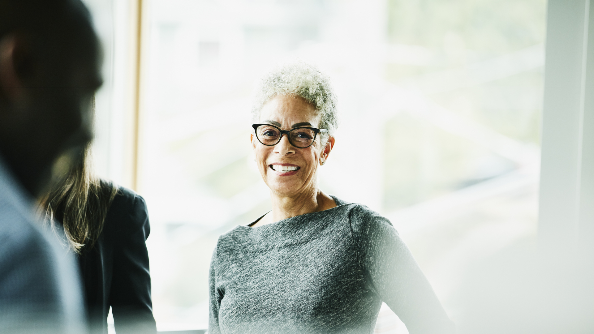 Portrait of smiling senior businesswoman in discussion with coworkers