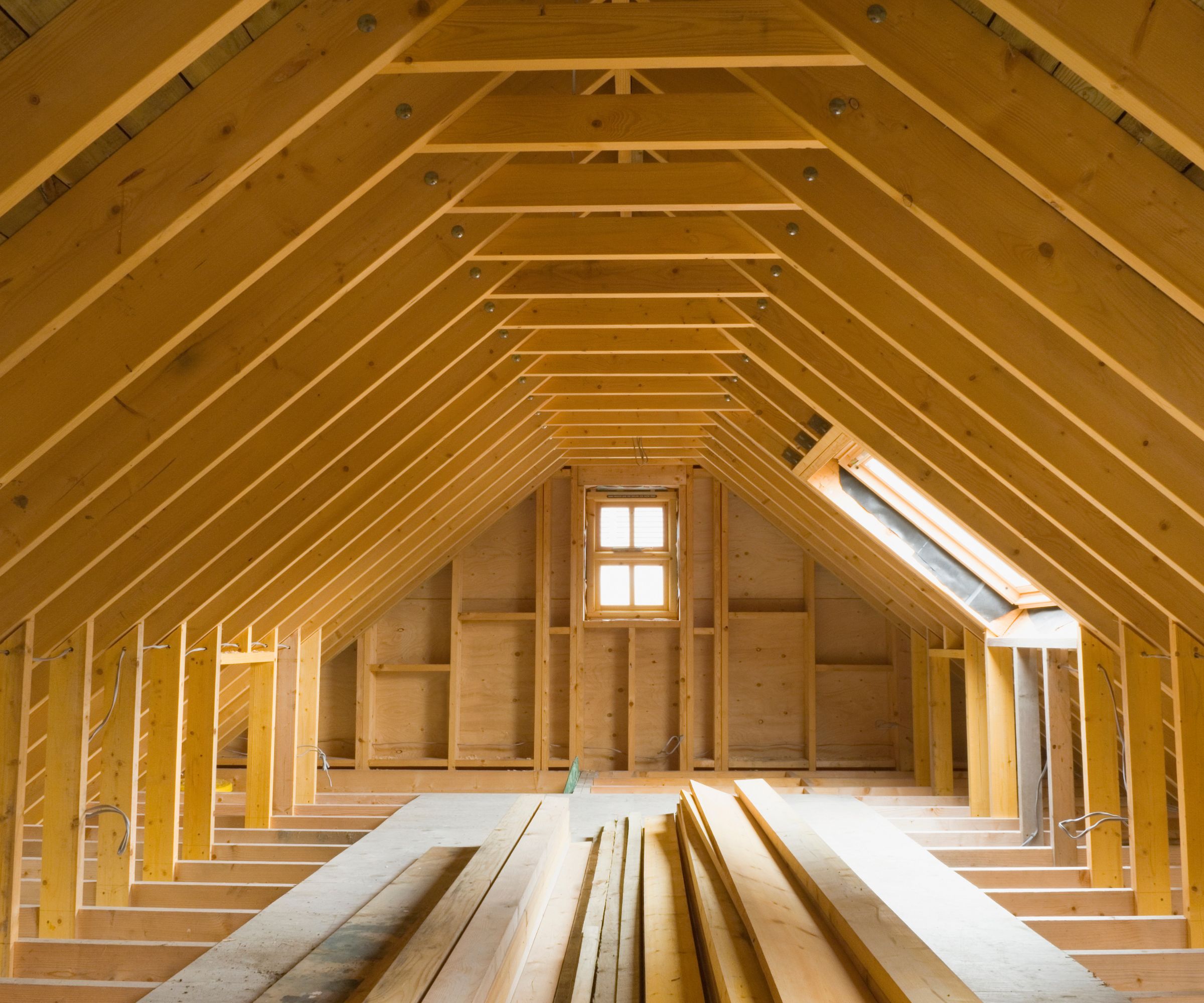 A wooden attic structure exposed, brightly lit by a ceiling window.