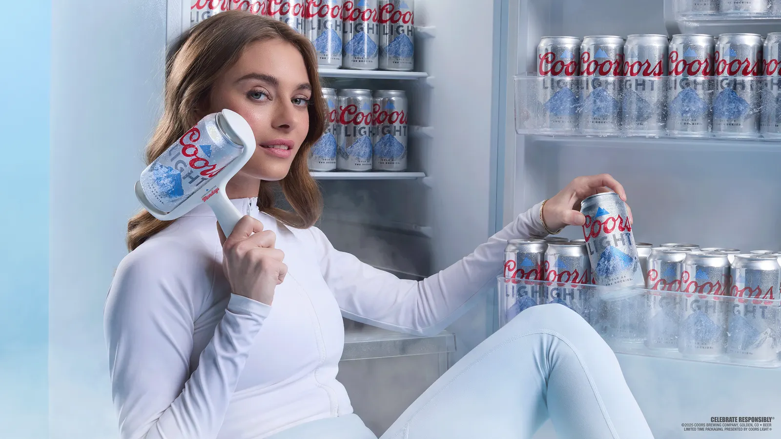 A woman sits in an icy room and uses a Coors Light can as a face roller.
