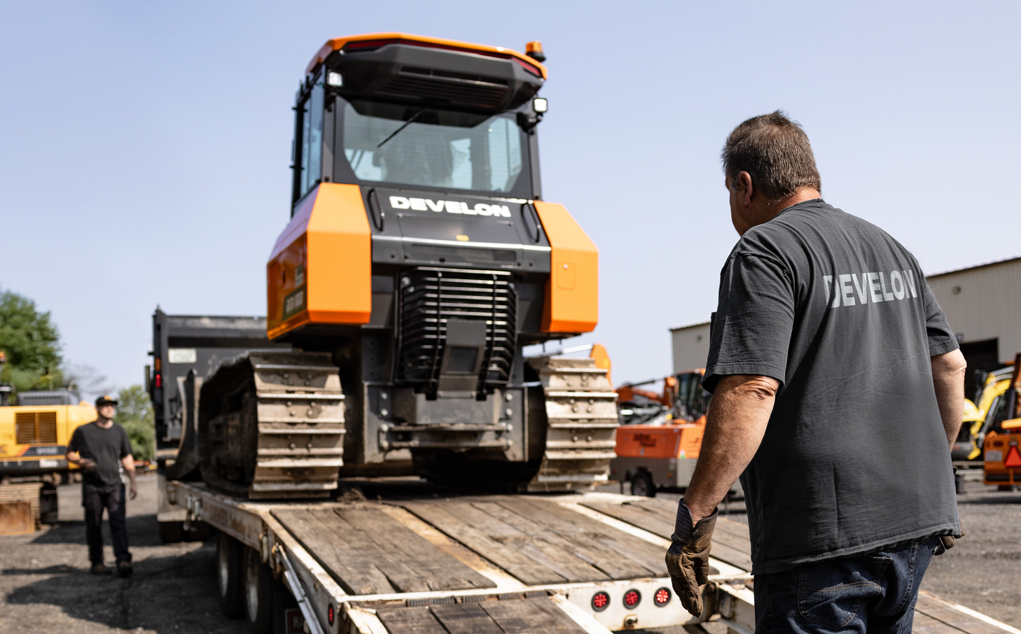 DEVELON dealer professionals unloading a DEVELON dozer off of a trailer.