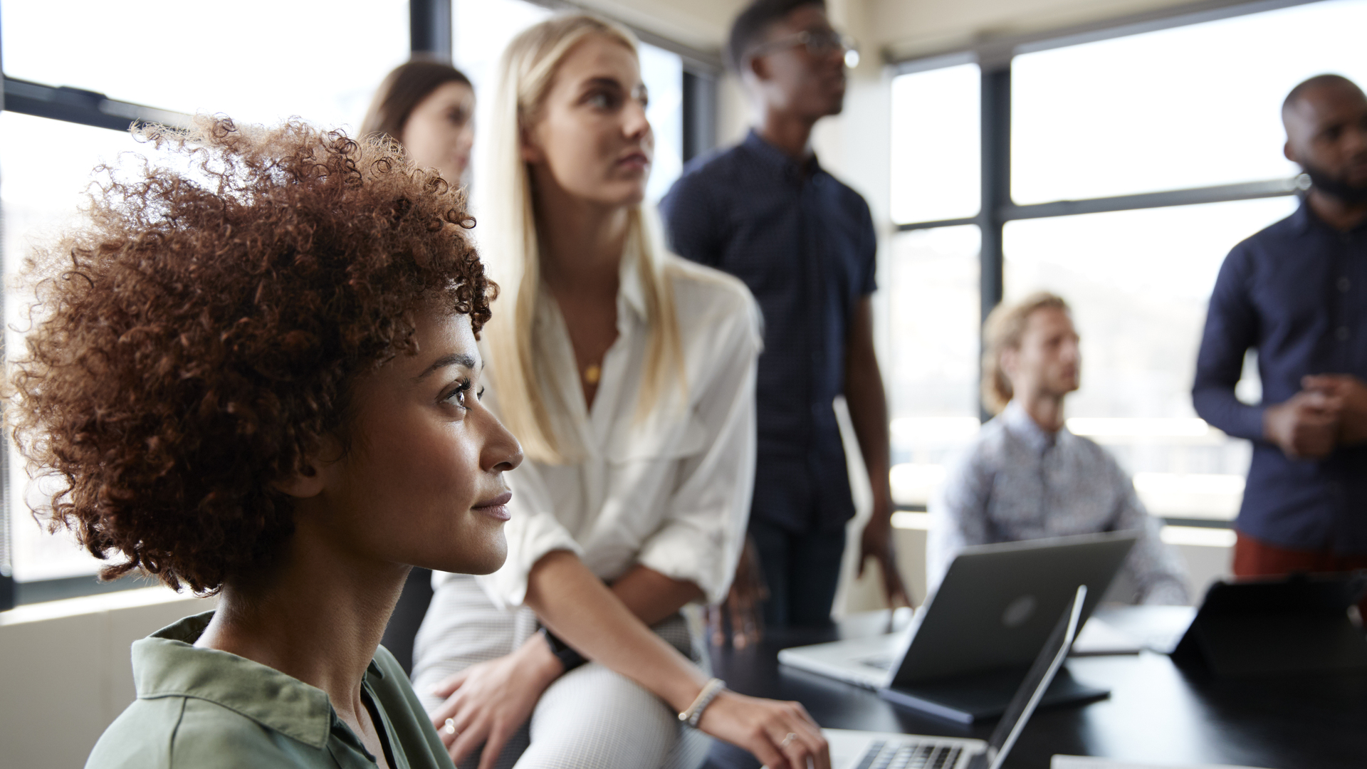 Close up of creative business colleagues listening to an informal presentation in a meeting room