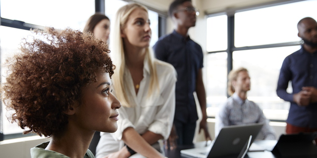 Close up of creative business colleagues listening to an informal presentation in a meeting room