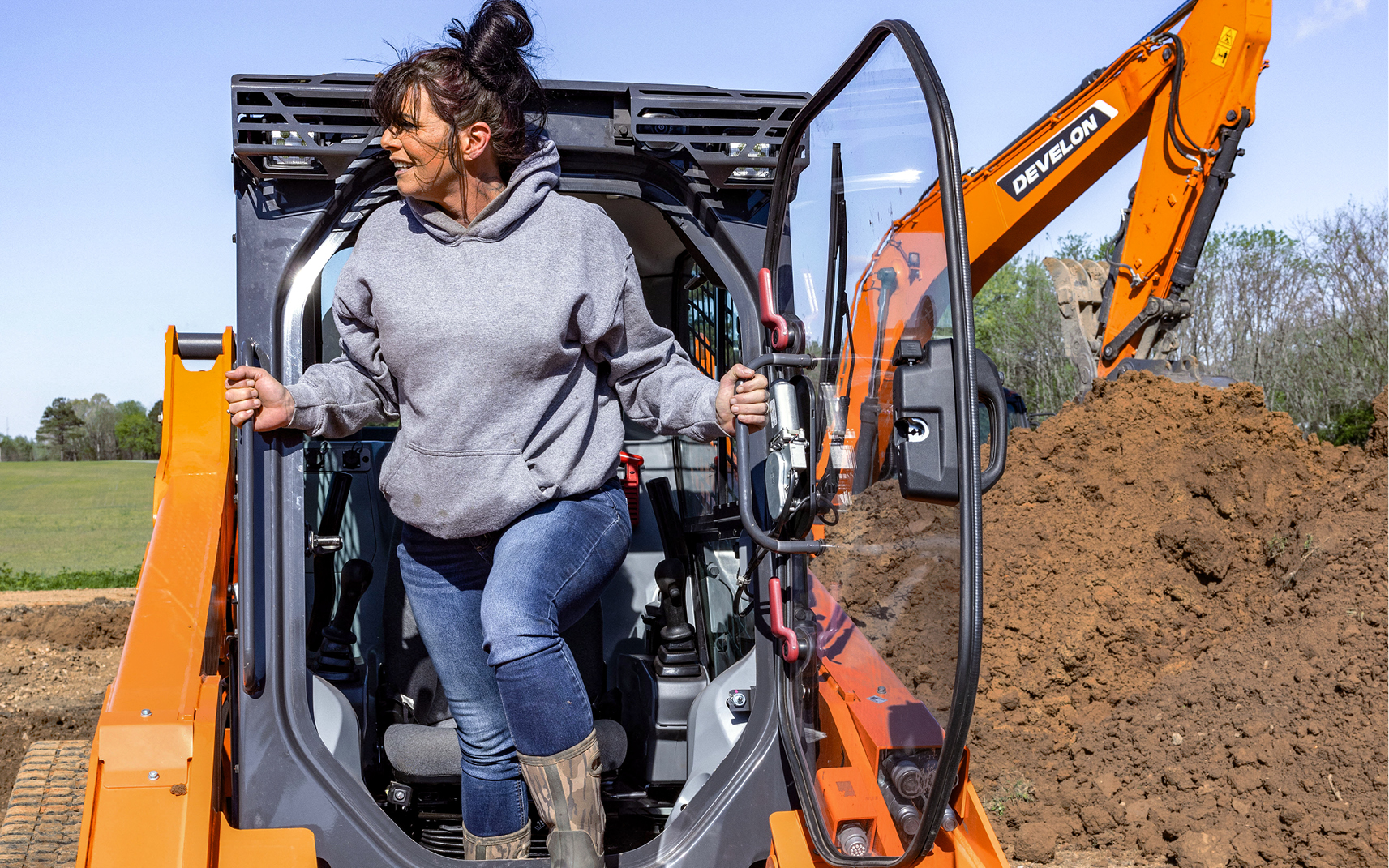 An operator exits the cab of a DEVELON compact track loader.