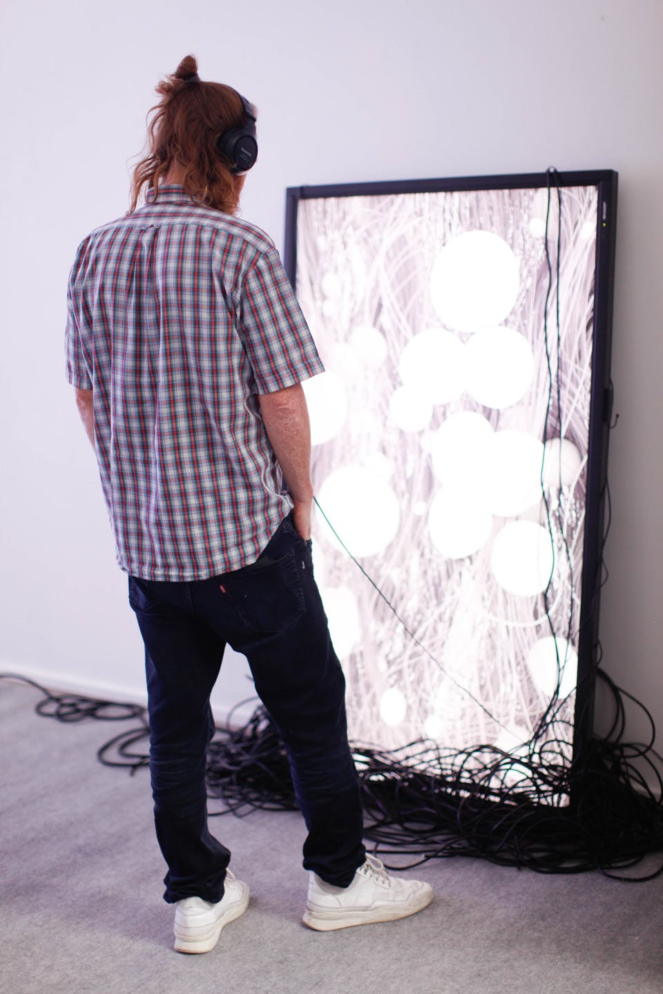 Man wearing headphones viewing bright digital art screen installation