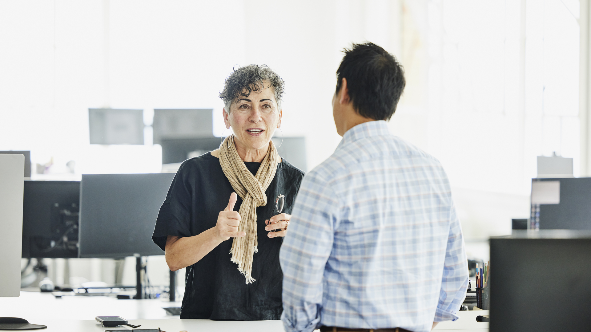 Medium wide shot business owner discussing project with colleague in office