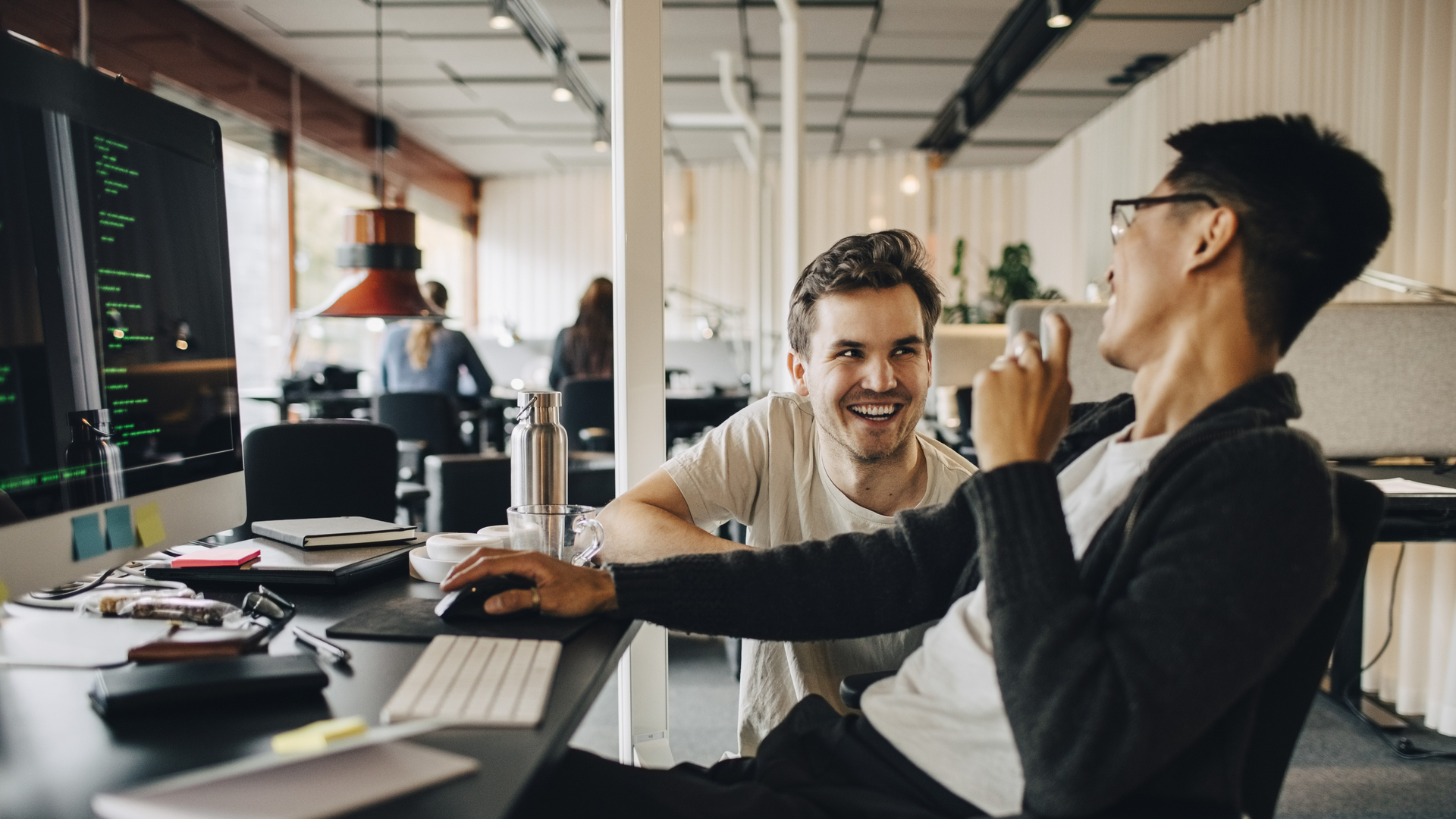 Happy multiracial computer programmers laughing while working at tech-startup office