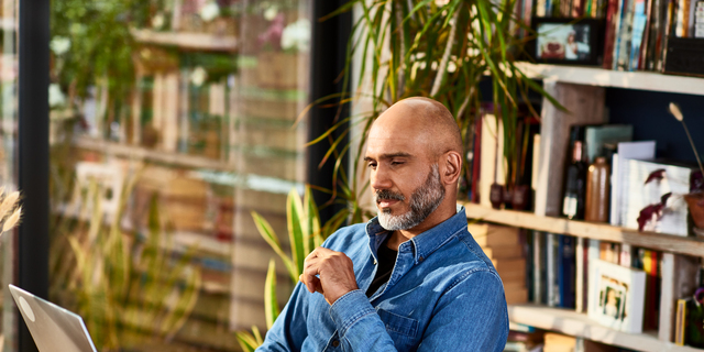 Mature businessman sitting at home watching laptop