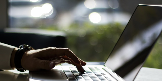 Businessman pushing a button on a laptop keyboard, close up