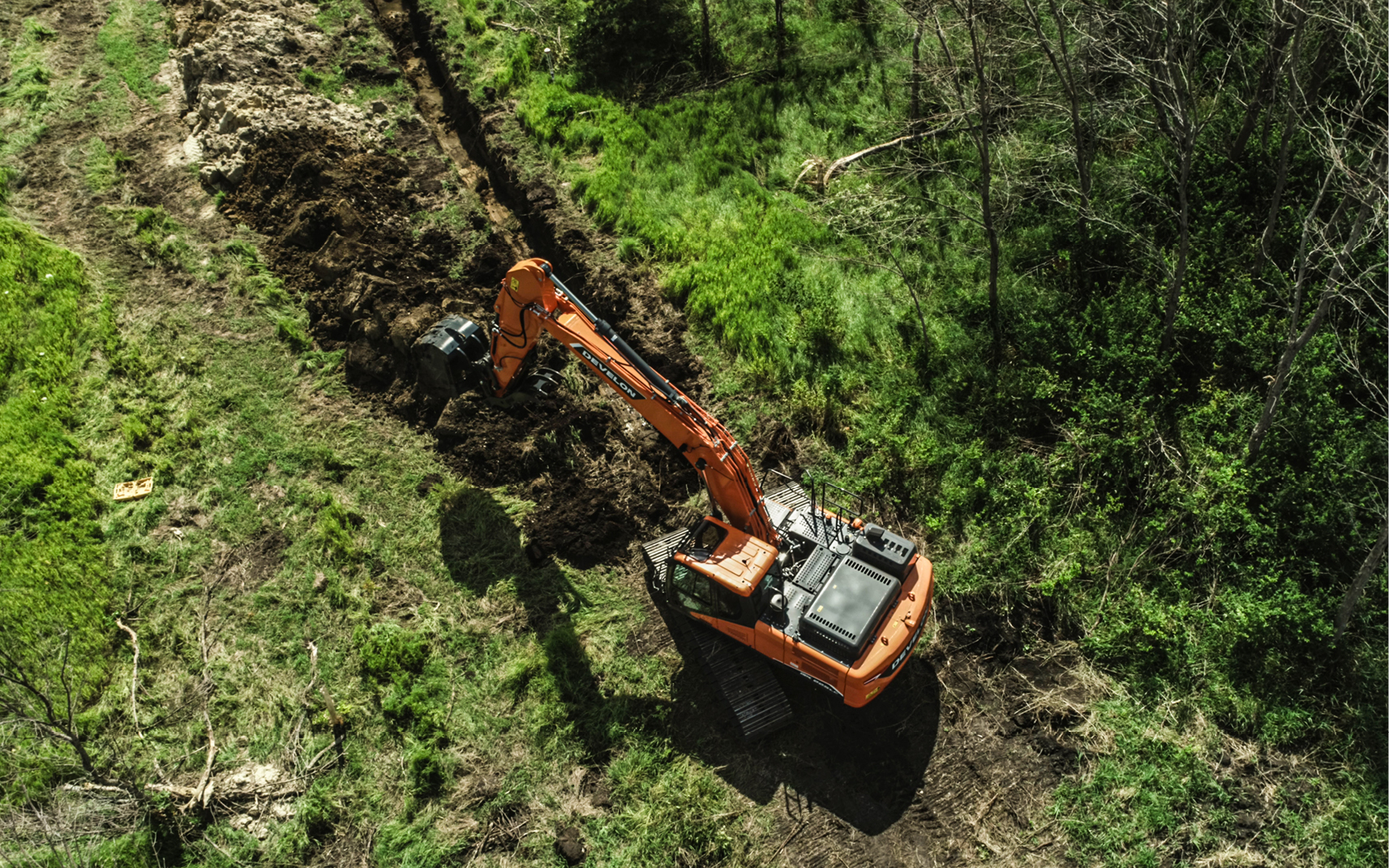 An aerial view, taken by a drone, of a DEVELON excavator working at a job site.