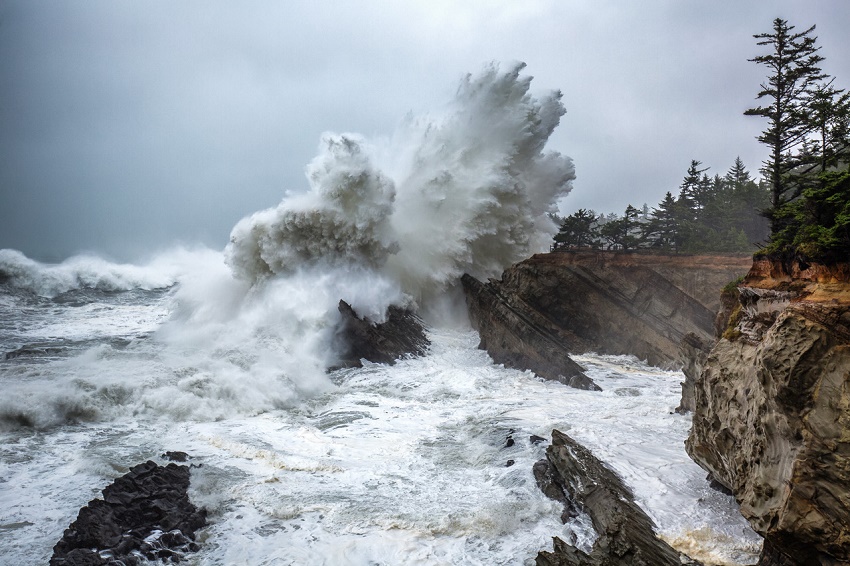 A photo of a wave smashing into the jagged Oregon coastline