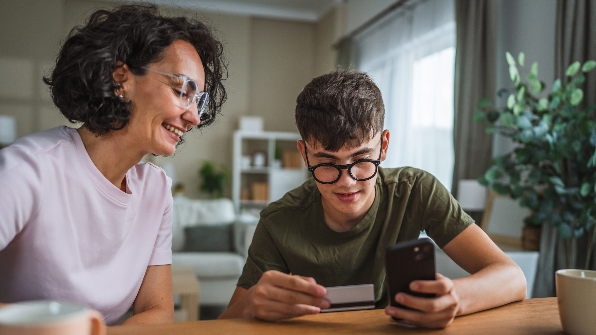 mom and son shopping online together, use mobile phone and credit card