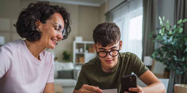 mom and son shopping online together, use mobile phone and credit card