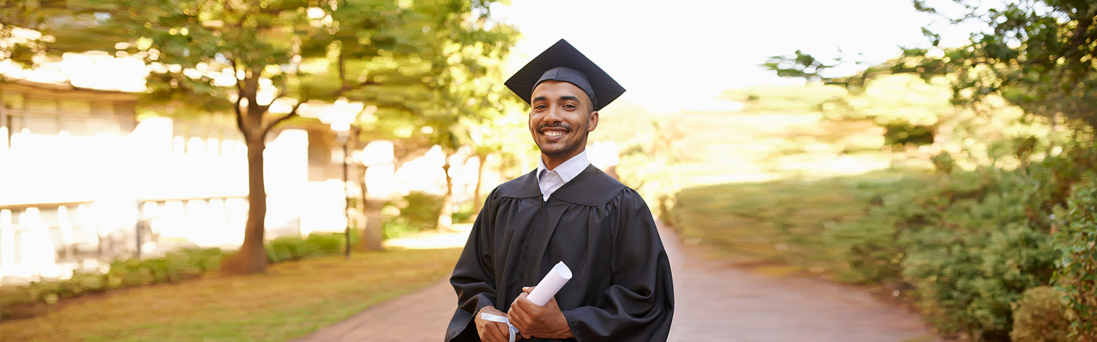 student holding his diploma in his a graduation gown