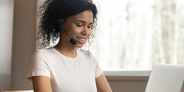 Young mixed race woman wearing headphones typing on computer