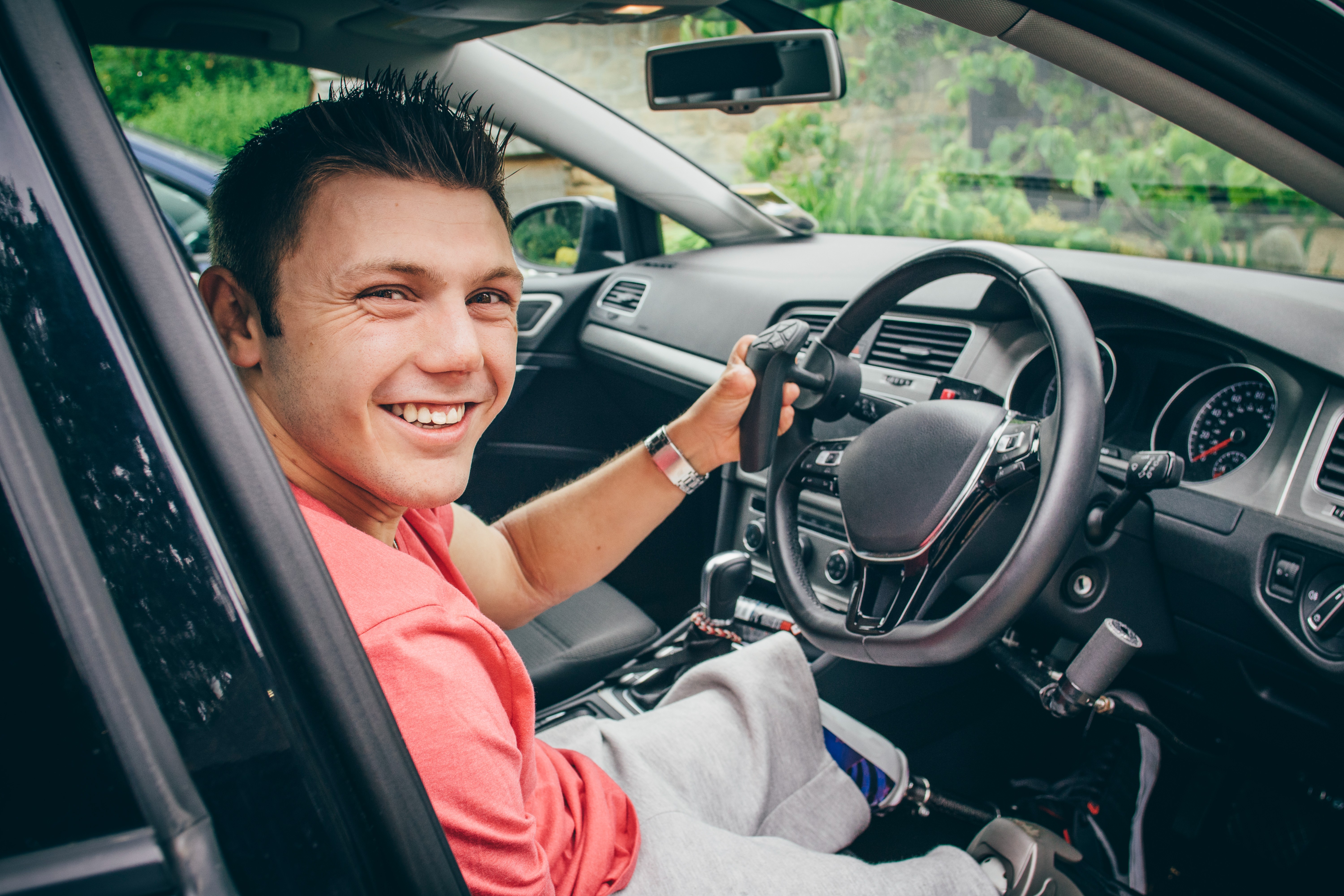 Disabled driver seated at his adapted Motability Scheme car with the door open smiling at the camera.