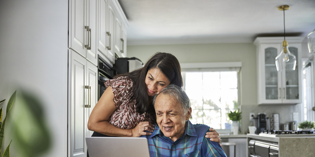 Daughter assisting father on how to use the computer