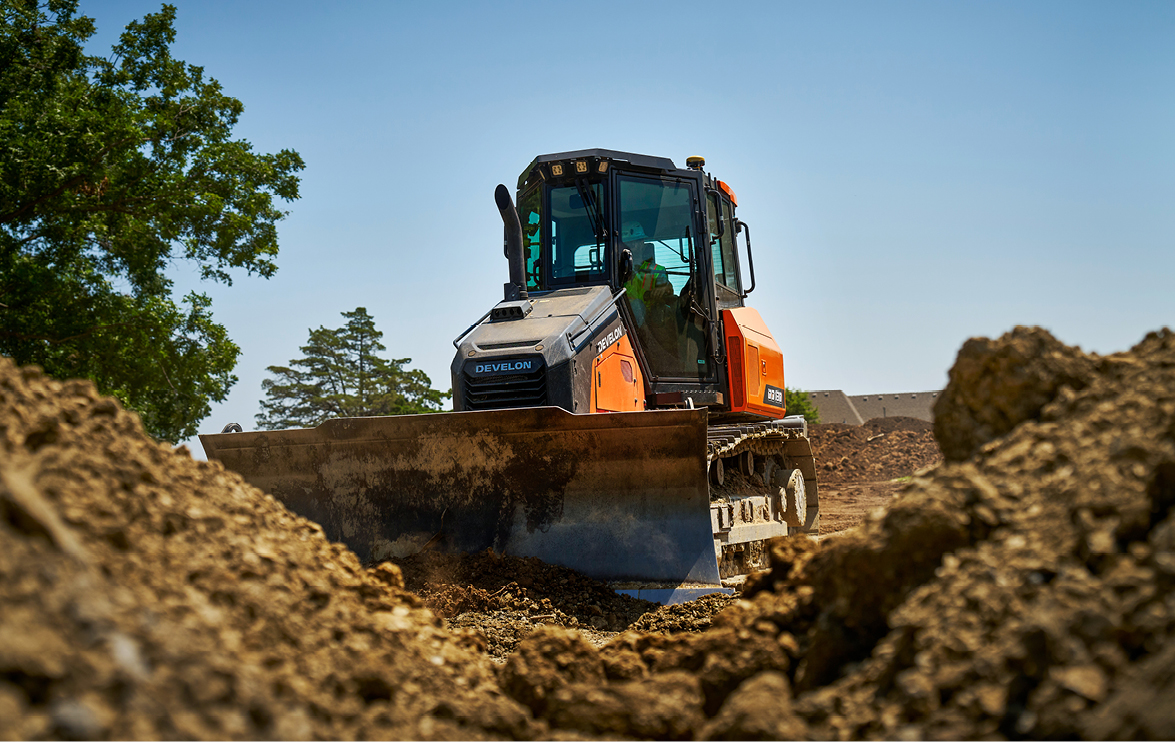 A DEVELON DD130 dozer pushing dirt on a jobsite.