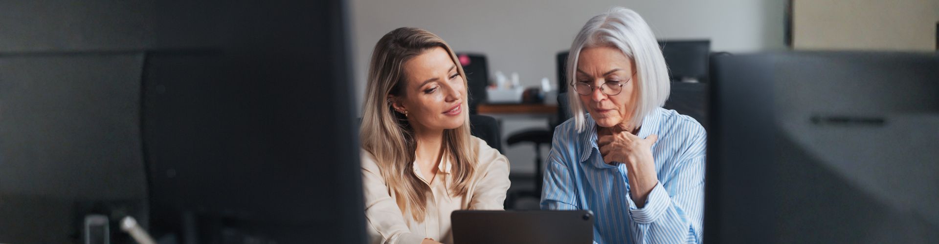 Two adult women sitting together and looking at a tablet