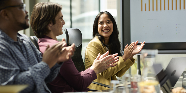 Happy businesswoman clapping in meeting room