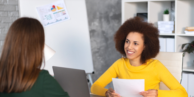 Interview between businesswoman hr director and job candidate. Recruitment manager holding paper cv and talking hiring for job female