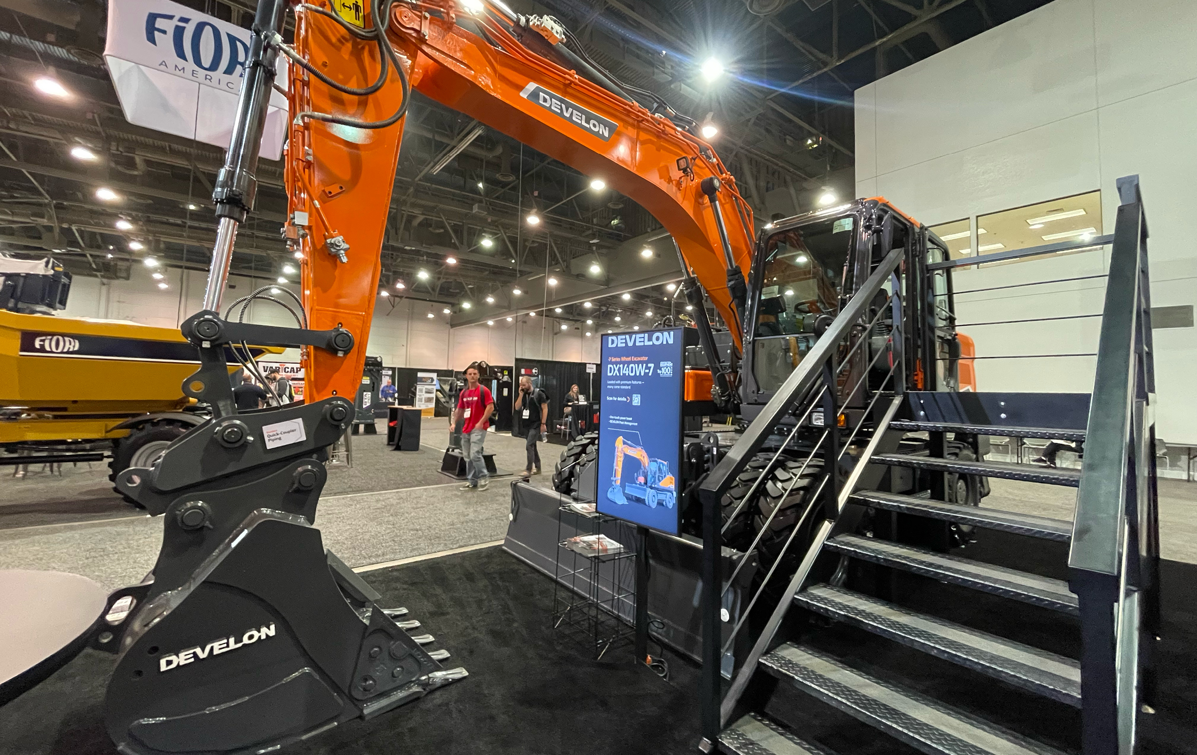 Attendees pass by DEVELON DX140W-7 wheel excavator at World of Concrete 2024.
