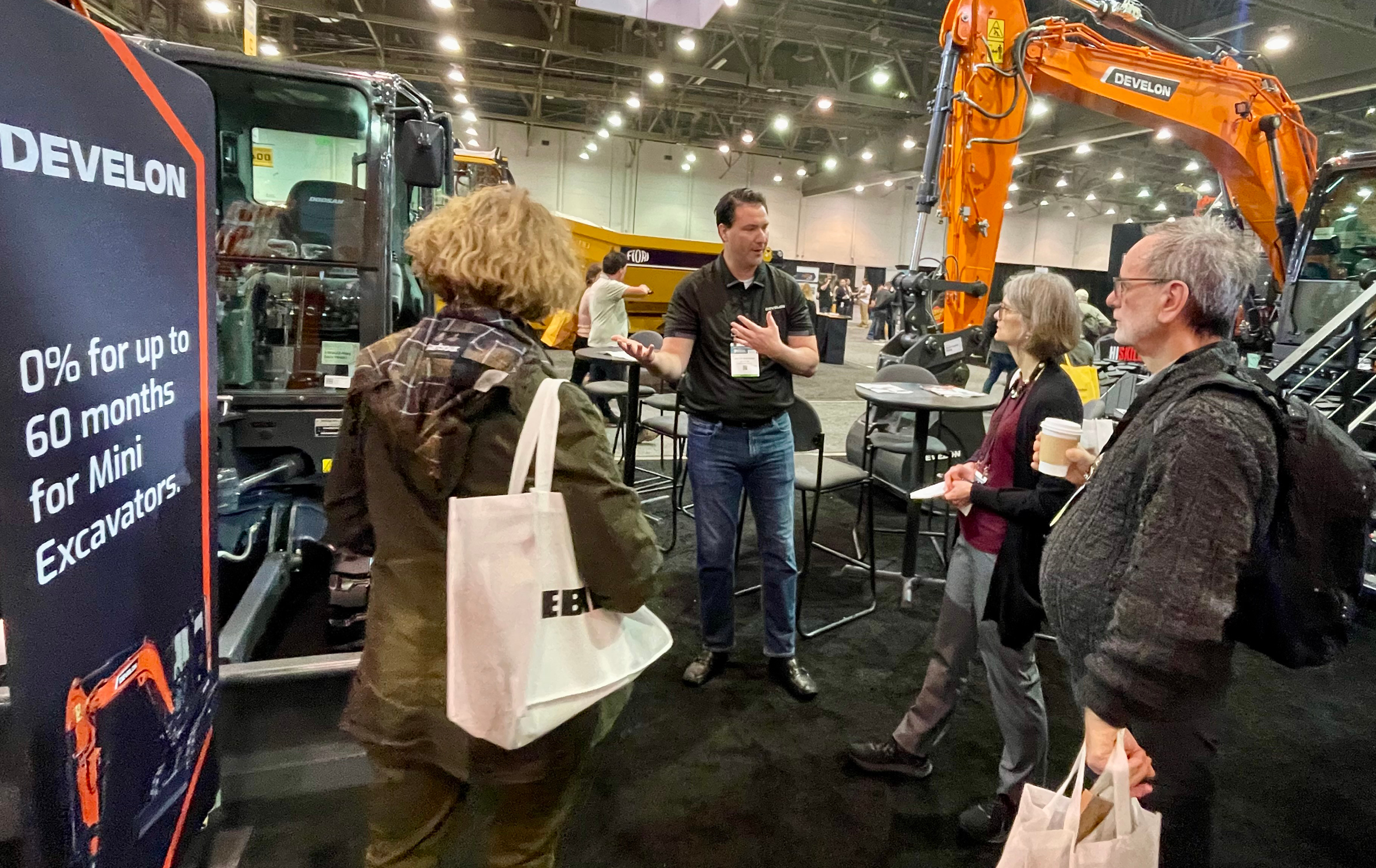 DEVELON representative speaks with attendees near DX140W-7 wheel excavator.