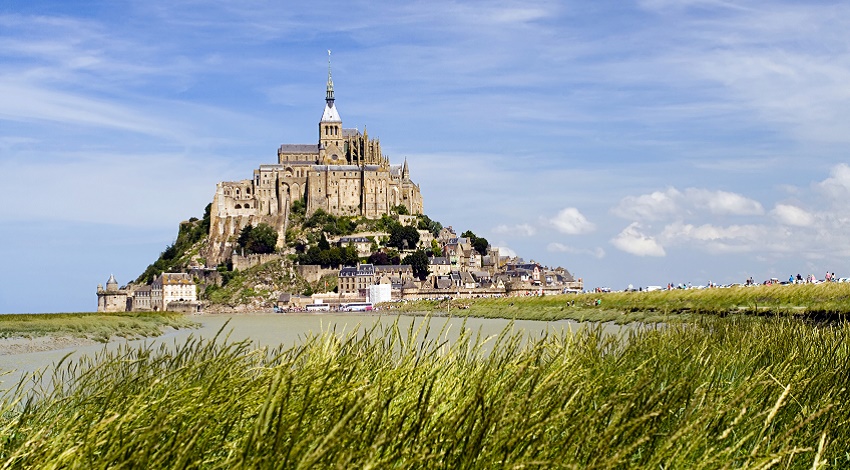 A medieval town on a hill surrounded by the ocean in France