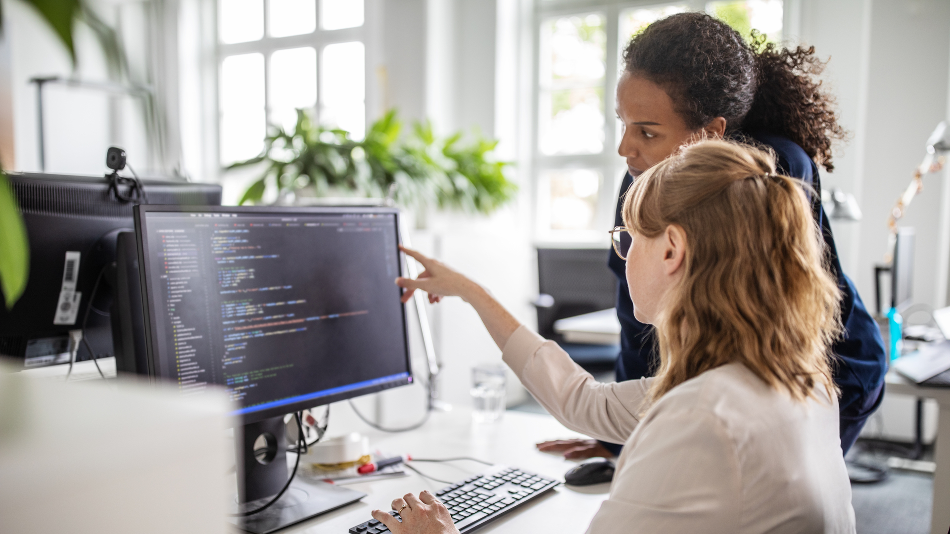 Coworkers discussing computer program in office