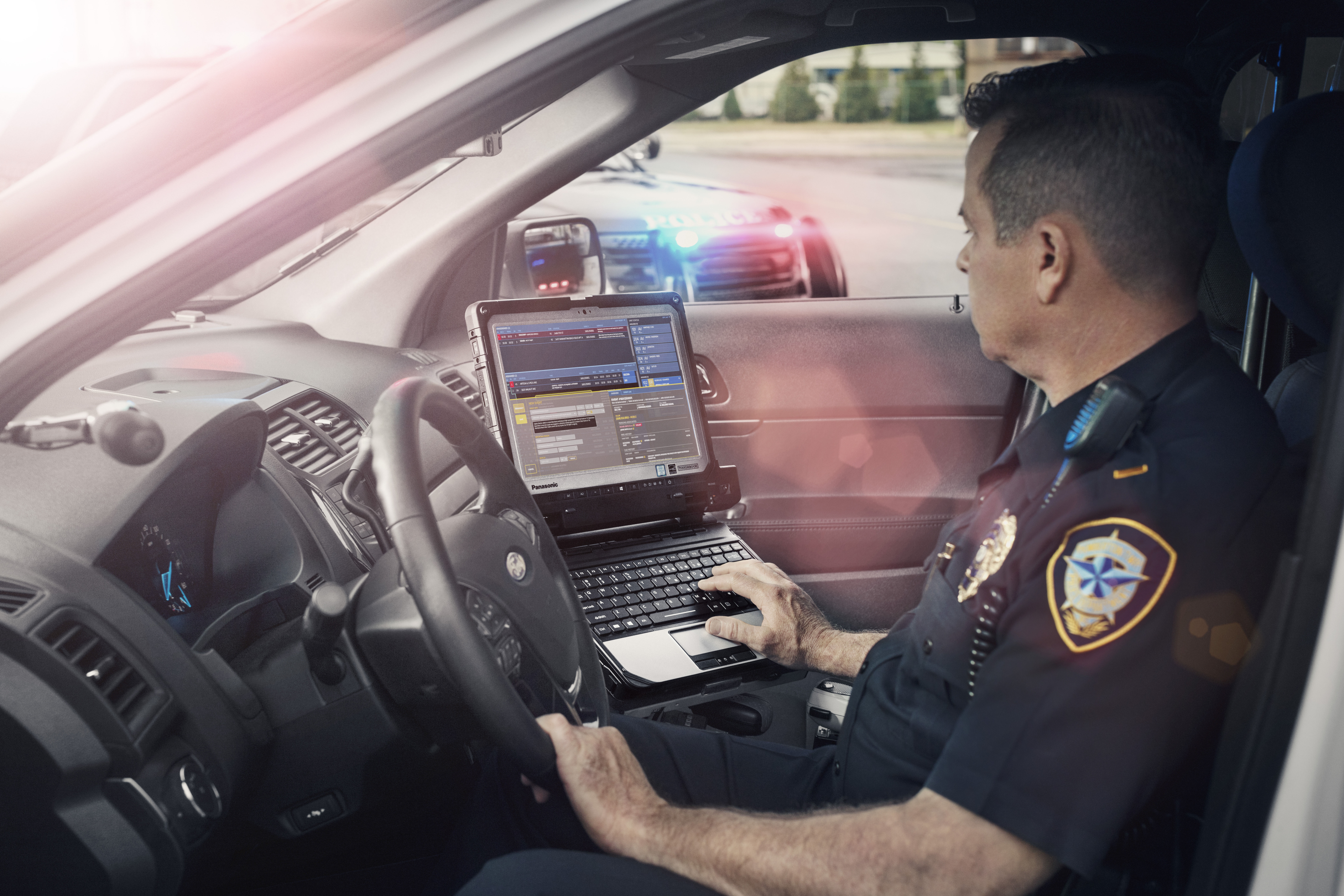 A law enforcement officer uses police technology in a cruiser on the job.