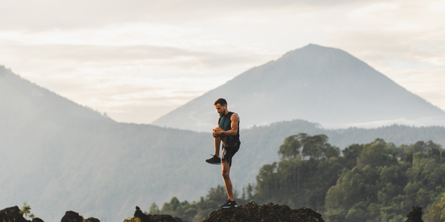 Man doing stretching and preparing for workout and running outdoors. Amazing mountain view on background. Adventure sports concept.