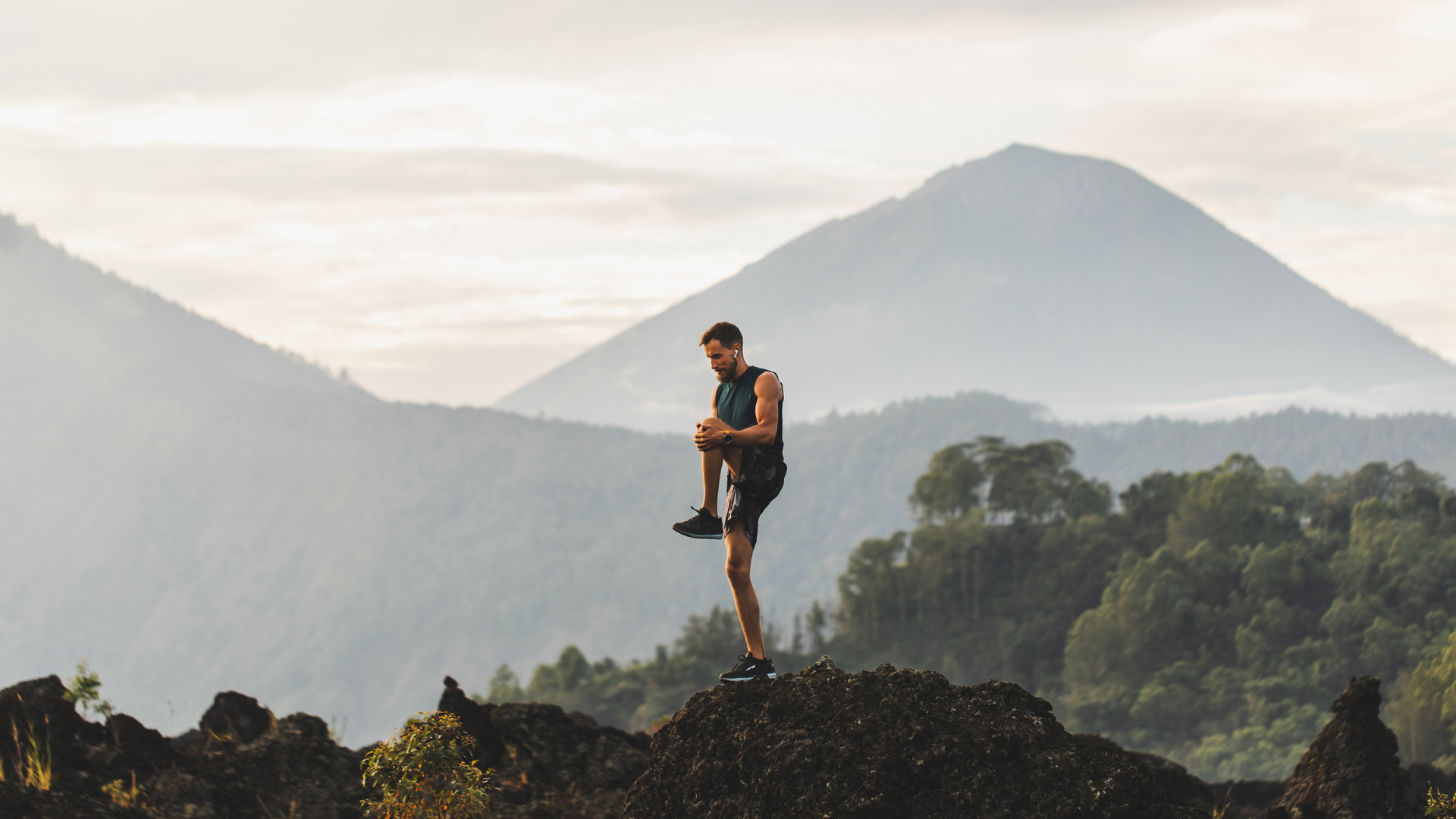 Man doing stretching and preparing for workout and running outdoors. Amazing mountain view on background. Adventure sports concept.