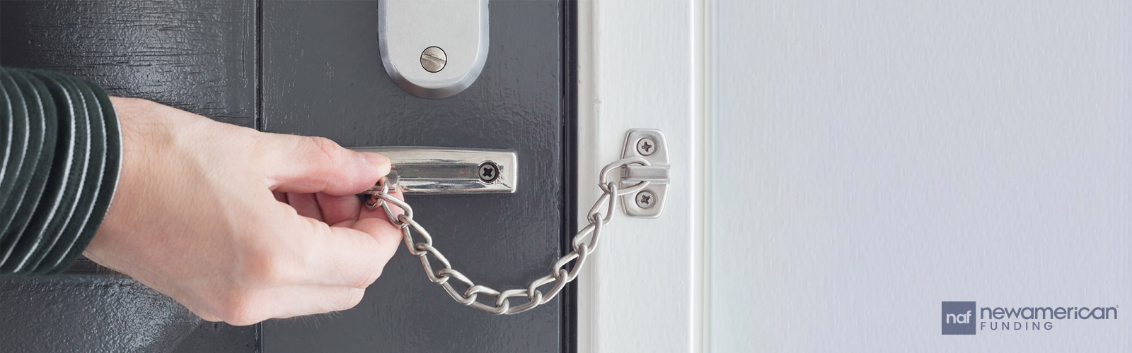 A hand closes a chain lock across a door