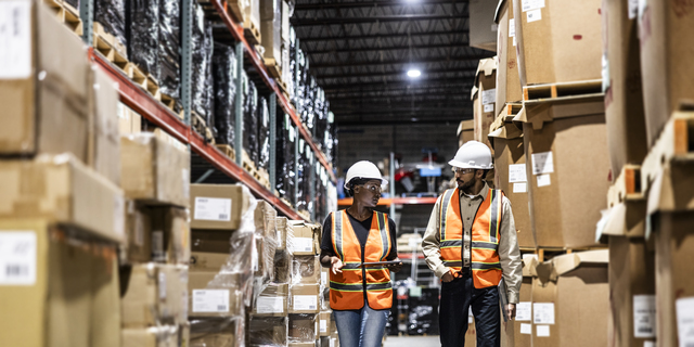 Warehouse employees walking in aisle of warehouse