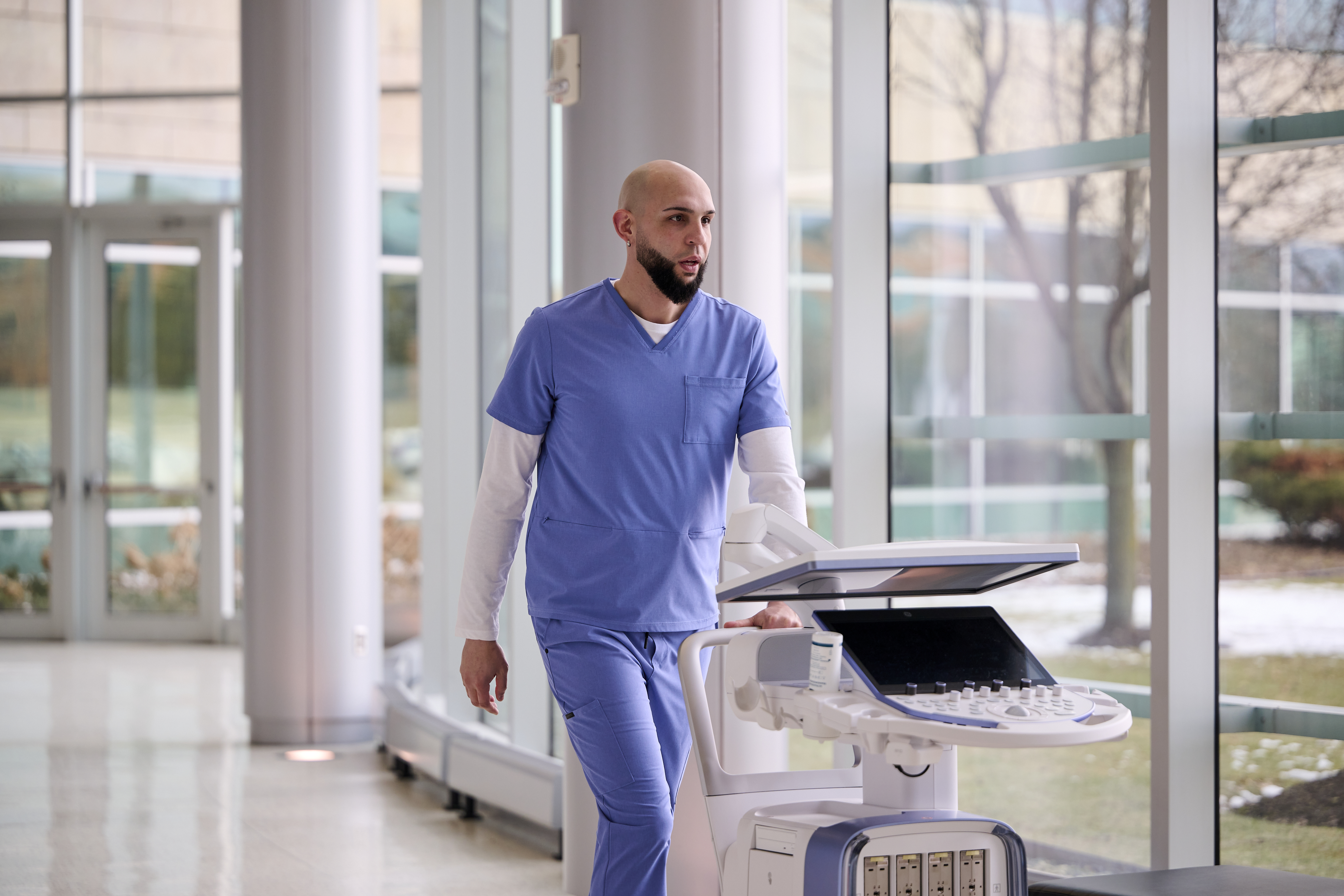 Sonographer pushes ultrasound system down a hallway