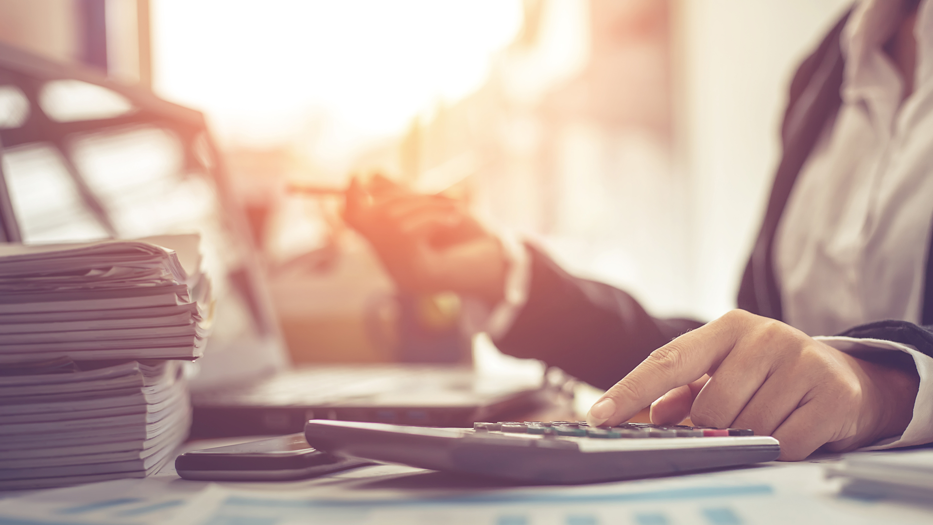 Business woman using calculator and writing make note with calculate. Woman working at office with laptop and documents on his desk