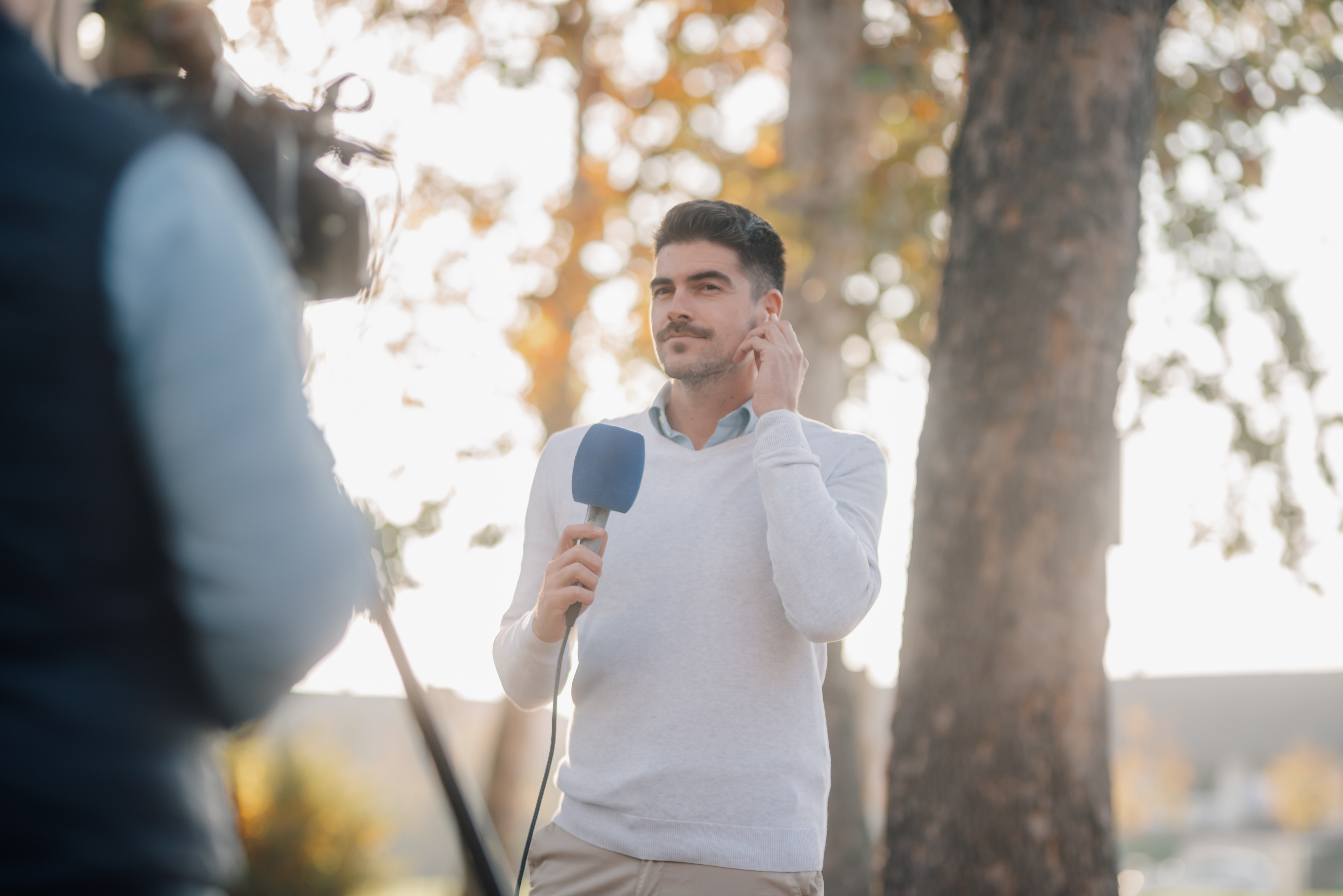 In the midst of remote video production, a man stands with a microphone with a camera off screen.