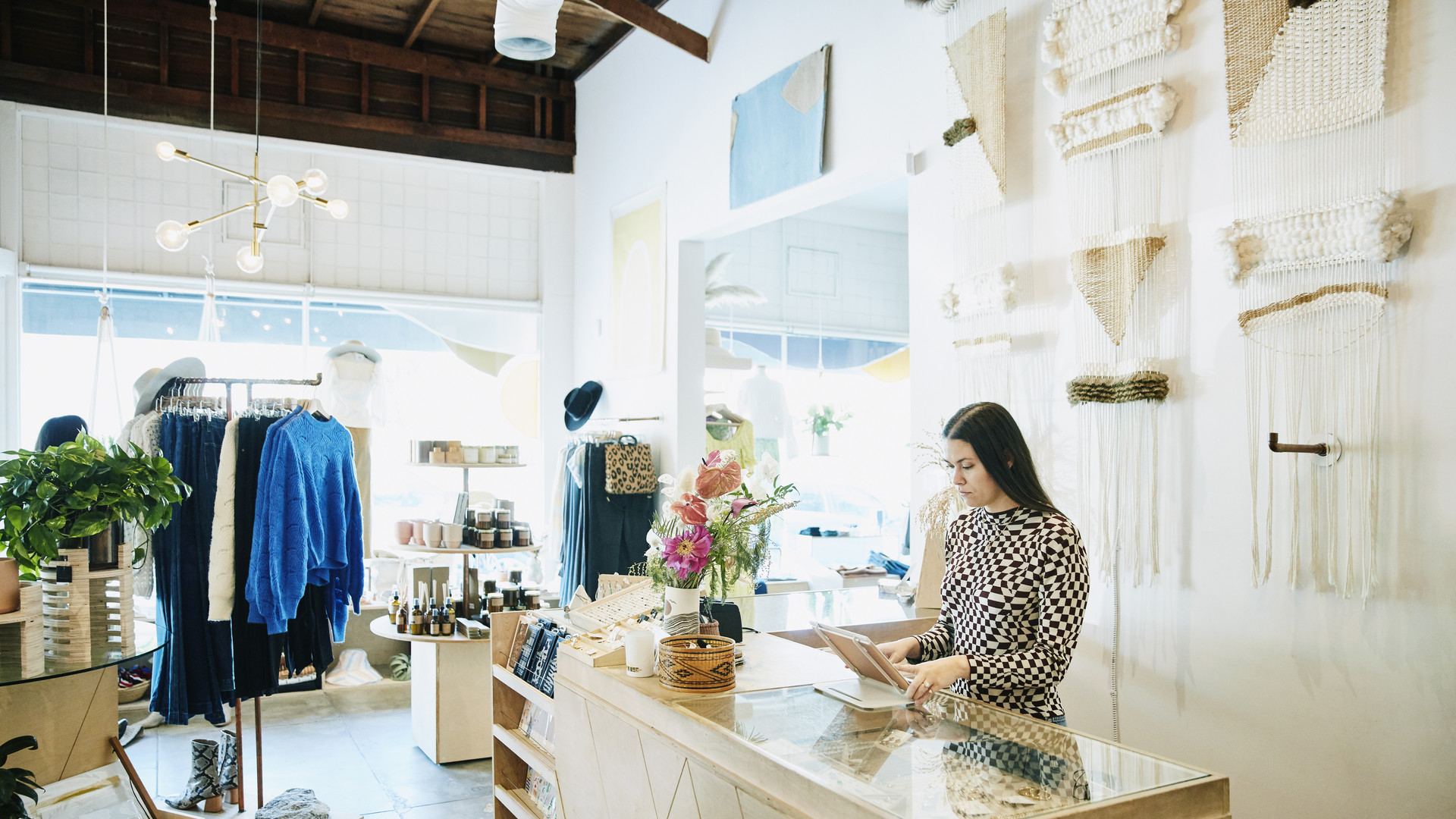 Shop owner working on digital tablet behind counter in clothing boutique