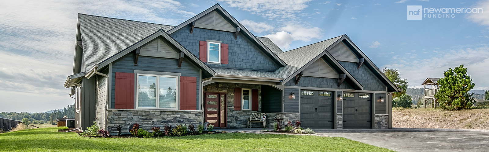 A nice ranch-style home with a dark blue exterior and red accents sitting on a well kept lawn