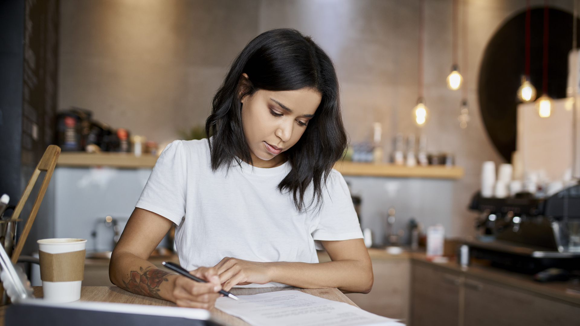 Female cafe owner signing papers calculating business expenses