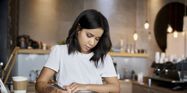 Female cafe owner signing papers calculating business expenses