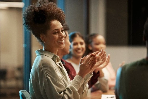Image of services business executives sitting in a row, smiling and clapping 