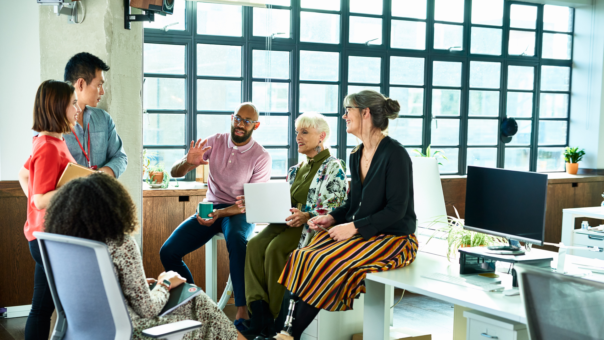 Business colleagues in meeting with female amputee sitting on desk