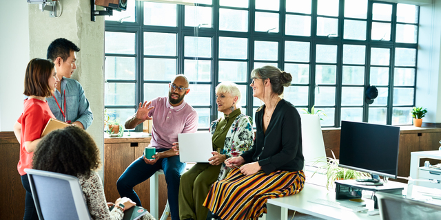 Business colleagues in meeting with female amputee sitting on desk