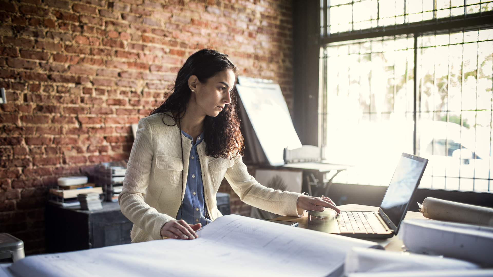 Businesswoman looking over architecture blueprints in office