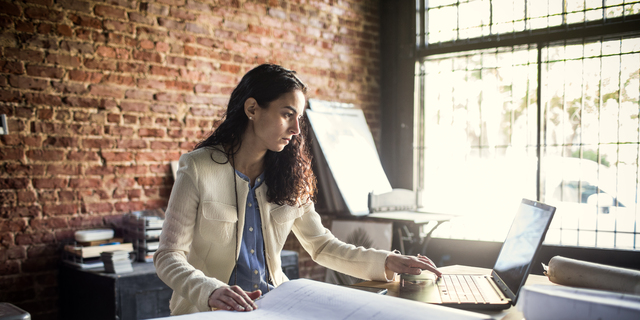 Businesswoman looking over architecture blueprints in office